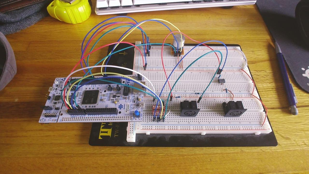 A breadboard with an STM32F4 Nucleo, MIDI jacks, an encoder, and switches.